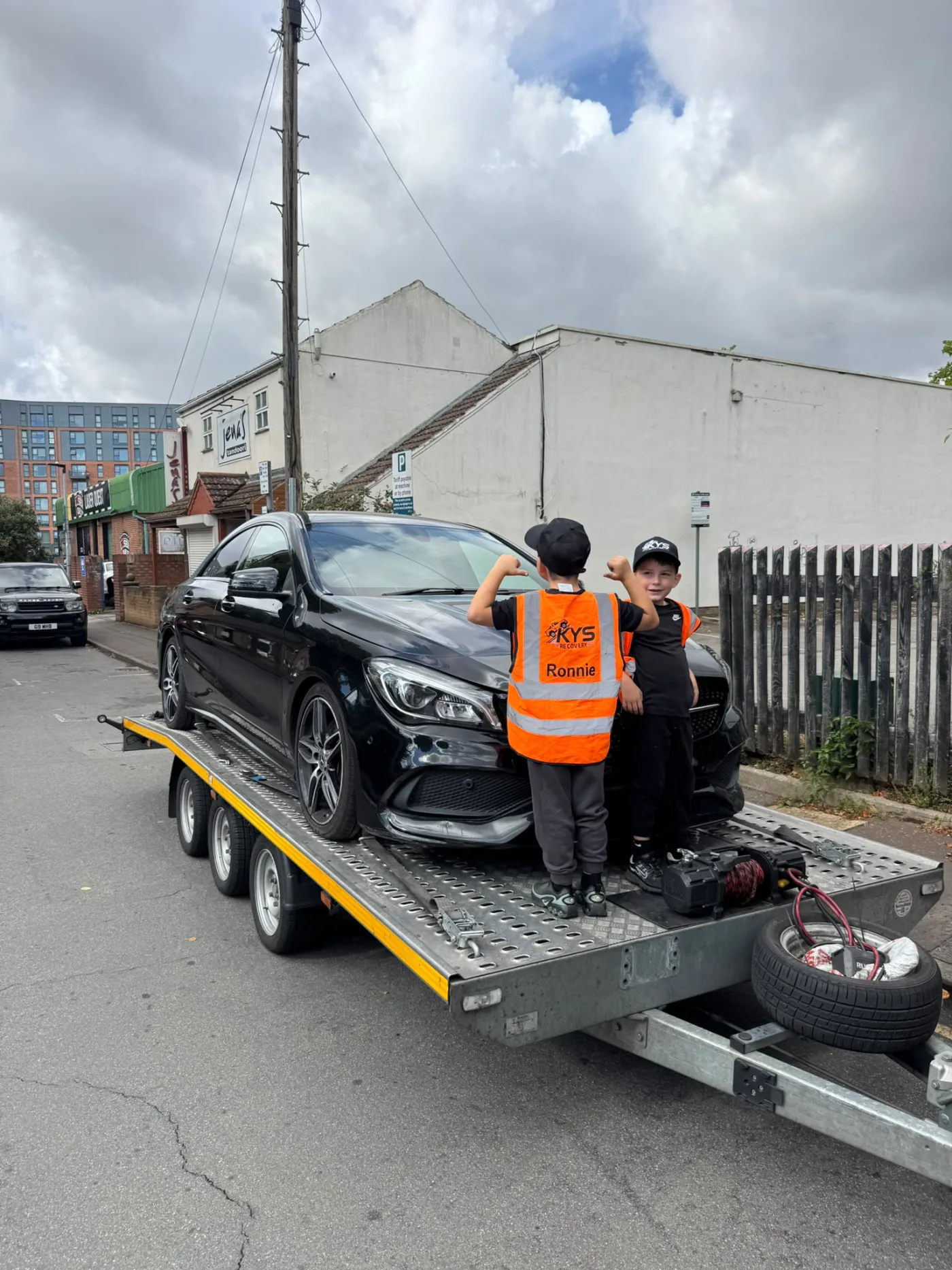 Two children wearing KYS Recovery clothing beside a recovered vehicle